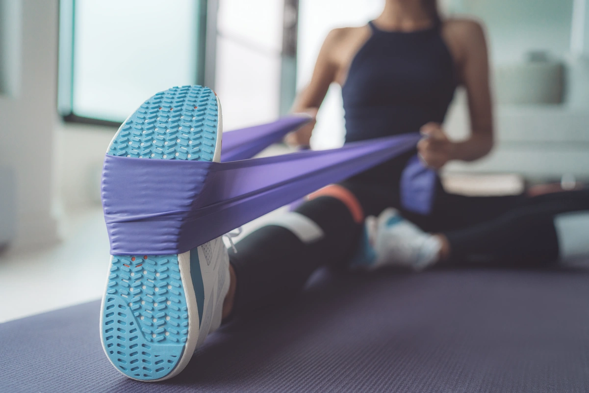 A woman is stretching her leg on a blue mat.
